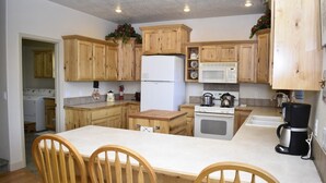 A kitchen with wooden cabinets, a refrigerator, a microwave, a stove, and a coffee maker.