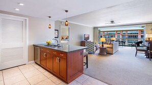 Een moderne keuken met een centraal eiland, een zithoek met een bank en stoelen, en uitzicht op een gebouw met balkons.
