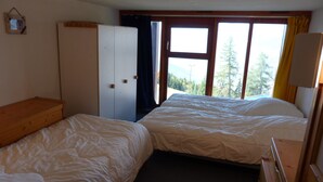 A bedroom with two beds, a wardrobe, and a window with a view of trees. - Comfortable duplex for 6 people in Arc 1800 (Les Arcs 1800)