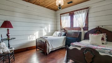 A bedroom with two wooden beds, a red lamp, and a teddy bear on a chair.