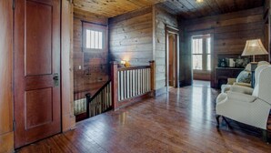 A spacious room with wooden floors, a staircase, and a seating area with a lamp. - Gorgeous 20s Historic Mini Mansion. King & Queens. Downtown Strip. (Wylie)