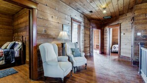 A wooden interior with two armchairs and a table, a bed in the background, and a wooden floor. - Gorgeous 20s Historic Mini Mansion. King & Queens. Downtown Strip. (Wylie)