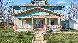 A two-story house with a front porch, a central entrance, and a small front yard. - Gorgeous 20s Historic Mini Mansion. King & Queens. Downtown Strip. (Wylie)
