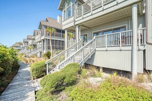 A coastal residential area with wooden boardwalks, beachfront properties, and a clear sky.