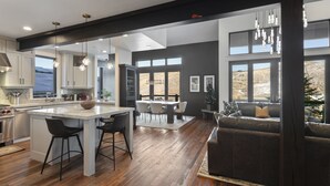 A modern kitchen with a central island, dining area with a table and chairs, and a cozy seating area with a couch. - Ski-In/Ski-Out Home, Private Hot Tub (Park City)