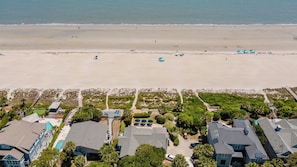 Vista aérea de un complejo turístico con casas, piscina y playa.