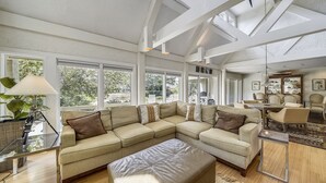 Ein geräumiges Wohnzimmer mit einer großen Eckcouch, einem Glastisch und einem Essbereich mit Stühlen.
