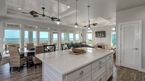 A spacious kitchen with a large island, white cabinetry, and a view of the ocean.