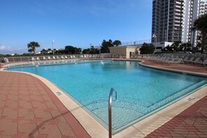 A swimming pool with a tiled deck, a metal handrail, and a clear blue pool.