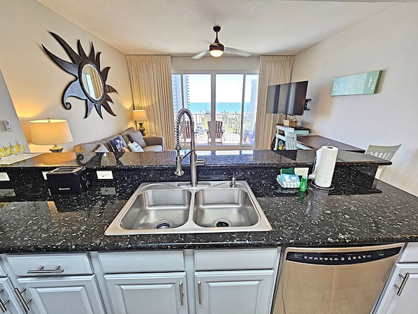 A modern kitchen with a double sink, granite countertop, and white cabinetry. - Available July 27th !! Cancellation Ariel Dunes 1- 605 in Seascape Resort. New bathroom! (Miramar Beach)
