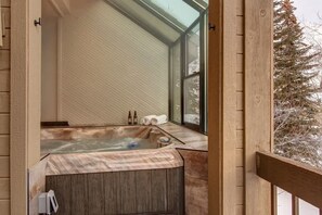 A hot tub with a view of a snowy tree outside.