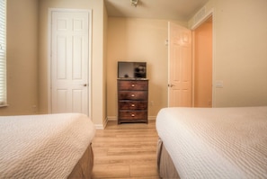 Une chambre avec deux lits, une commode et un téléviseur.
