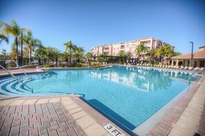 A swimming pool with a 3 FT depth marking, surrounded by palm trees and a multi-story building in the background. - 3BR Condo w  Resort Perks near Epic Universe! (Orlando)
