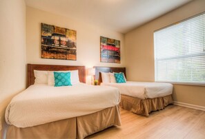 Une chambre d’hôtel avec deux lits, des têtes de lit en bois et une fenêtre avec des stores.