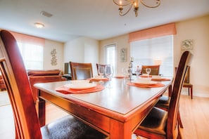 Un coin repas avec une table en bois, dressée pour quatre personnes, entourée de chaises.