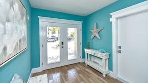 Un couloir aux murs de couleur turquoise, aux portes blanches et au plancher en bois.