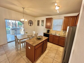 A kitchen with granite countertops, wooden cabinets, a built-in oven, and a refrigerator.