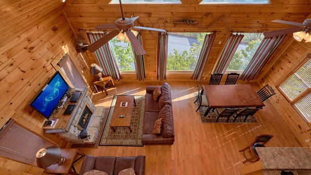 Une cabine spacieuse avec un intérieur en bois, un ventilateur de plafond, une cheminée, un téléviseur et un coin repas.