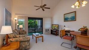 A living room with a sofa, coffee table, TV, and dining area with chairs and a table.