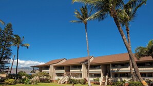 A multi-story hotel with a brown roof, balconies, and a staircase leading to the entrance.