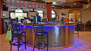 A bar area with a curved counter, bar stools, and a television mounted above the bar. - Town Home in Gated Resort with Lazy River & Waterslide Close to Attractions (Davenport)