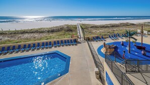 A pool area with a view of the beach, lounge chairs, and a water feature.