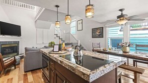 A modern kitchen with a central island, pendant lights, and a staircase leading to an upper level. - Abode on Woodside, private hot tub, walk to historic Main Street & trails (Park City)