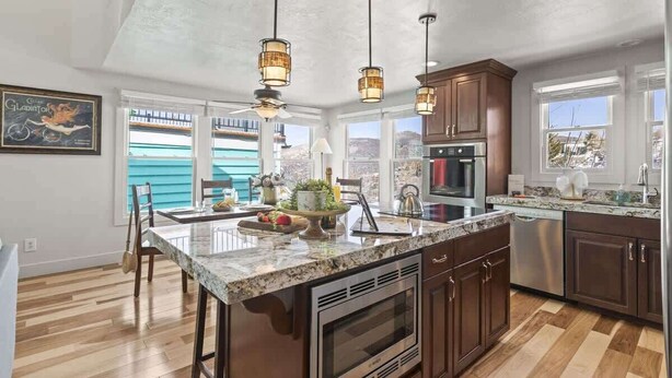 A kitchen with a large island, pendant lights, and a view of the outside. - Abode on Woodside, private hot tub, walk to historic Main Street & trails (Park City)