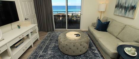 Una sala de estar con sofá, reposapiés y mueble para televisión.