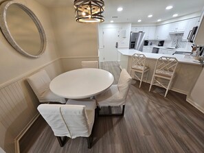 A modern kitchen with white cabinets, a round dining table, and a built-in island with a sink. - Beachfront Condo Stunning 7th Floor Views and tram at Westwinds in Sandestin. Private beach (Miramar Beach)