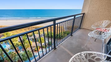 Un balcon offrant une vue dégagée sur la plage et la piscine.