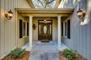 Stunning entrance with a symmetrical design, featuring a covered porch and a beautifully lit door.