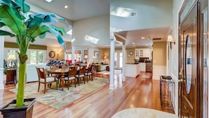 A spacious living area with a dining table, chairs, and a large potted plant.
