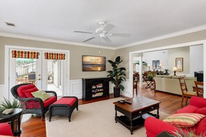 Ein Wohnzimmer mit Fernseher, Deckenventilator, Kamin und Essbereich.