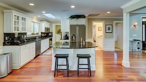 A modern kitchen with white cabinetry, a central island with stools, and a stainless steel refrigerator.