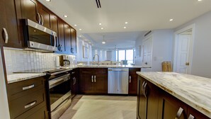 Una cocina moderna con armarios de madera oscura, electrodomésticos de acero inoxidable y encimera de mármol.