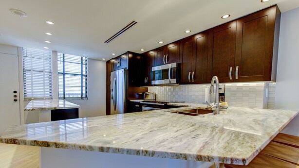 Una cocina moderna con armarios de madera oscura, electrodomésticos de acero inoxidable y una isla grande de mármol.