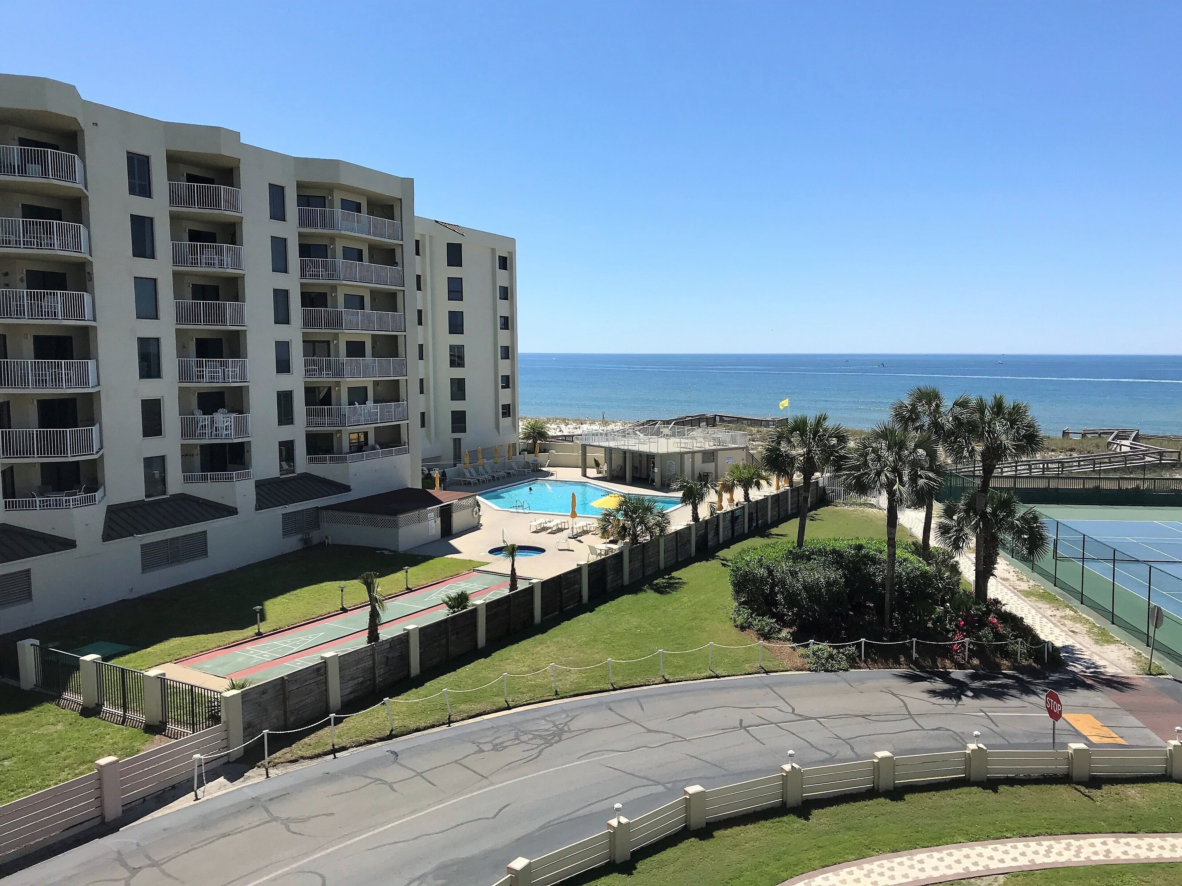 Un hôtel à plusieurs étages, doté de balcons, d’une piscine et offrant une vue sur l’océan.