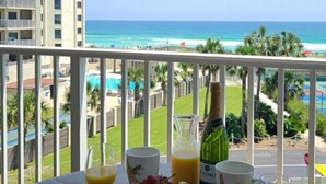 A balcony with a table set for breakfast, overlooking a beach and ocean. - 🌅Unit #401 –Unobstructed Gulf Views & Dolphin Watching from Your Balcony🌊🐬 (Destin)