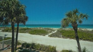 Uitzicht op een strand met palmbomen en een helderblauwe lucht.