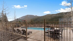Un espace extérieur clos, doté d’une piscine, de mobilier de jardin et offrant une vue sur les montagnes.
