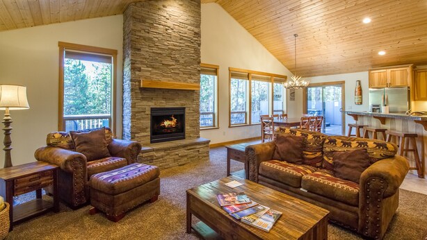 A cozy living room with a stone fireplace, leather sofas, and a wooden ceiling. - CAMA16 - Sharc Passes, AC, Pool and Ping Pong Tables, Hot Tub (Sunriver)