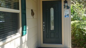 A dark green front door with a glass panel, a mailbox, and a welcome sign.