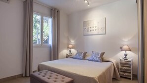 A bedroom with a bed, two bedside tables with lamps, a window with curtains, and a wall-mounted artwork. - Domaine Ghjulia - Casa Nebbiu (Patrimonio)