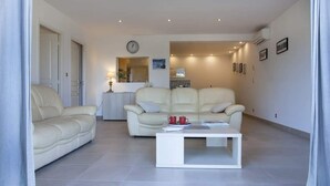 A modern living room with two cream-colored sofas, a white coffee table, and a small side table with red cups. - Domaine Ghjulia - Casa Nebbiu (Patrimonio)