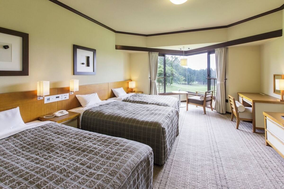 A hotel room with two beds, a desk, and a chair.