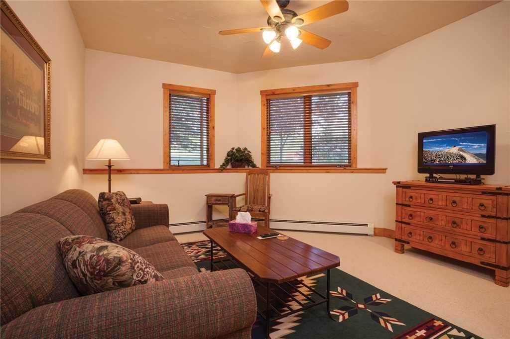 A living room with a sofa, a coffee table, a TV, and a ceiling fan.