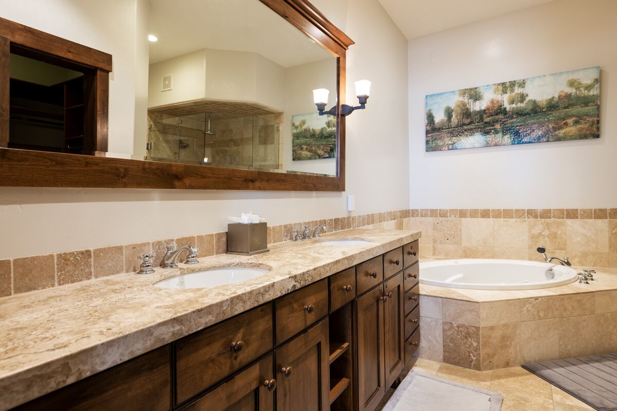 Une salle de bain avec deux lavabos, un grand miroir et un tableau accroché au mur.