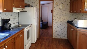 Une cuisine avec des meubles de rangement en bois, un réfrigérateur, une cuisinière, un four à micro-ondes et une machine à café.