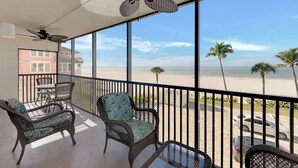 Un balcón con mobiliario de mimbre, un ventilador de techo y vista a la playa.